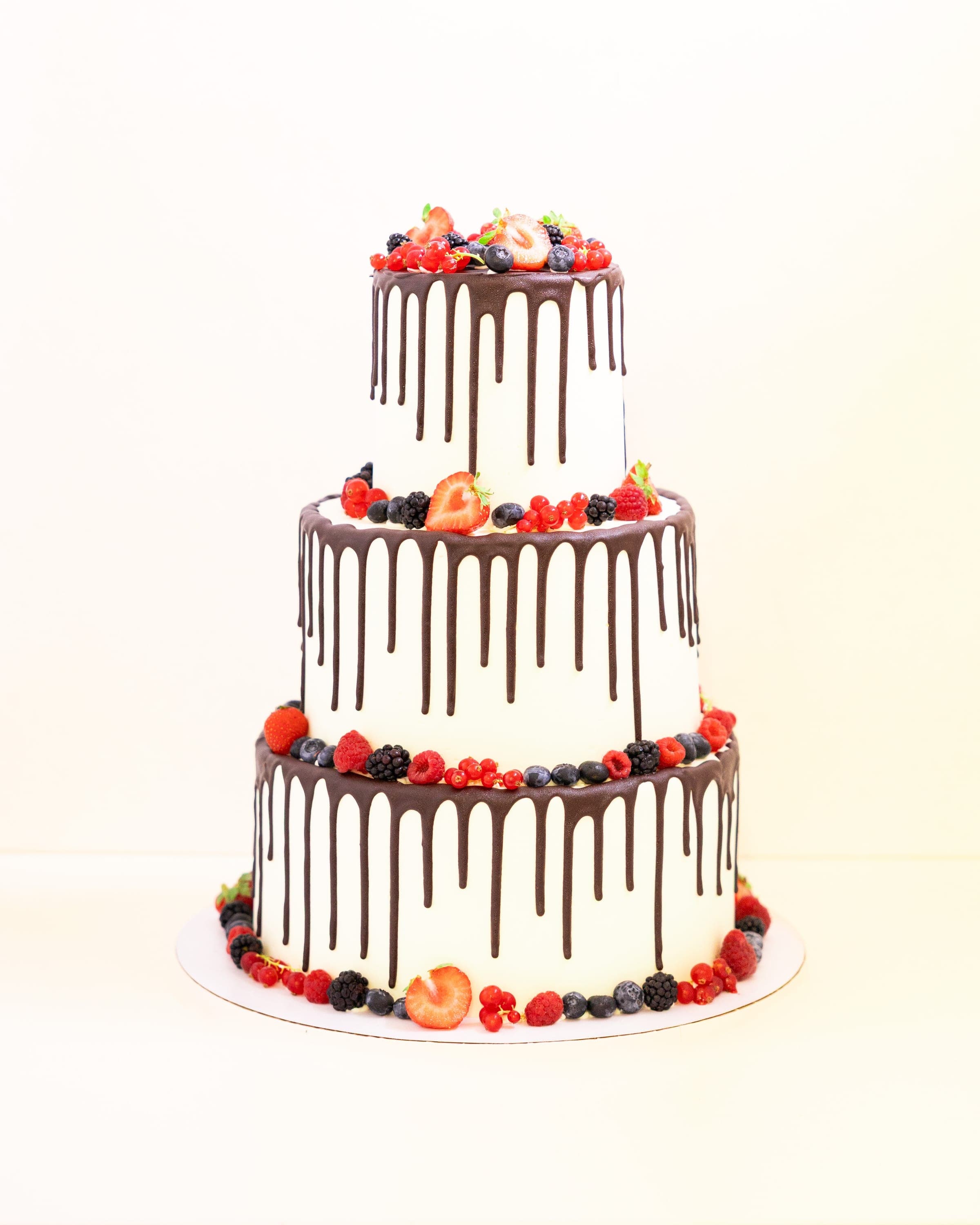 Dreistöckige Hochzeitstorte mit Schokoladendrip und frischen Beeren