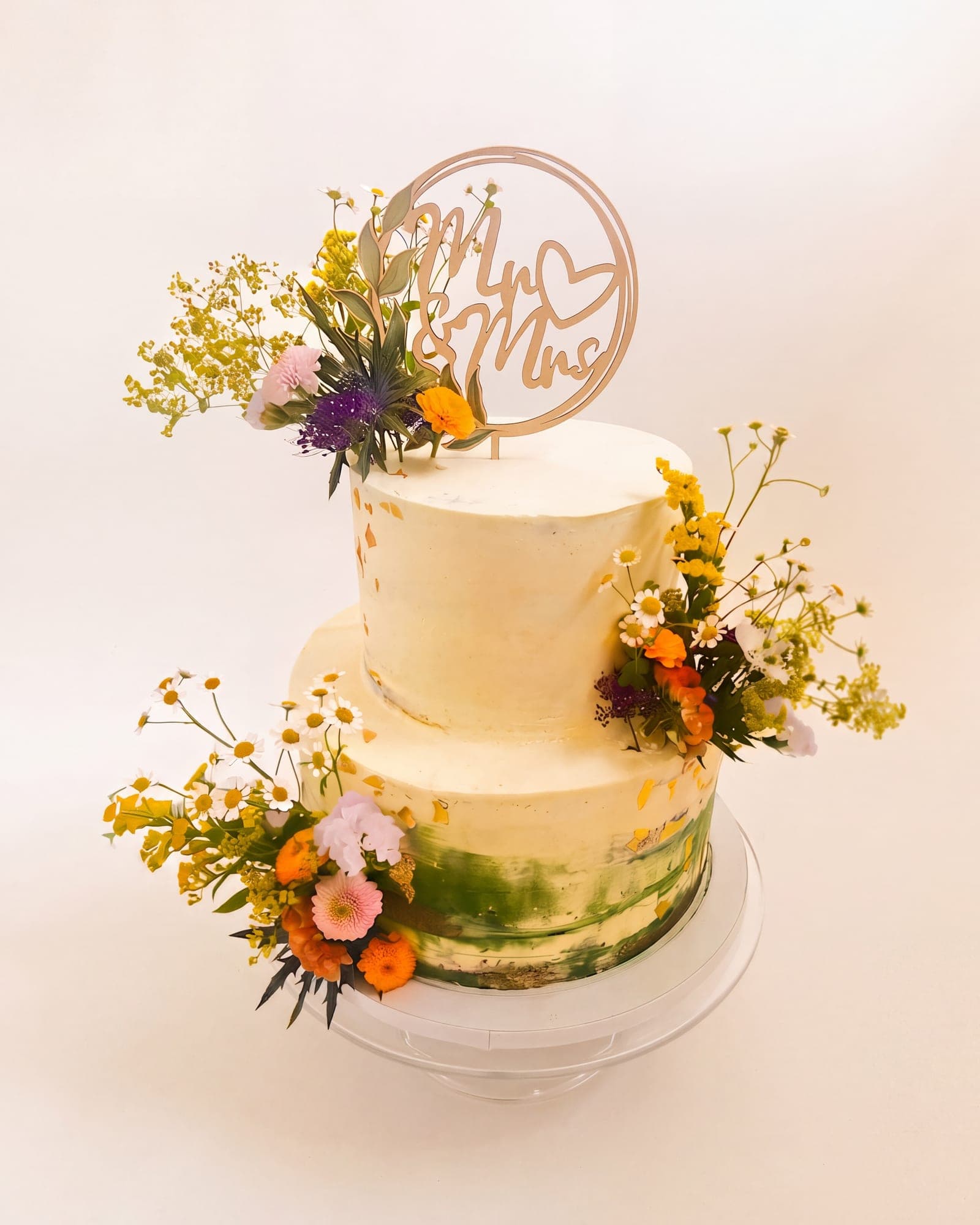Zweistöckige Semi-naked-Torte mit grünem Farbverlauf und Wiesenblumen in Gelb und Orange